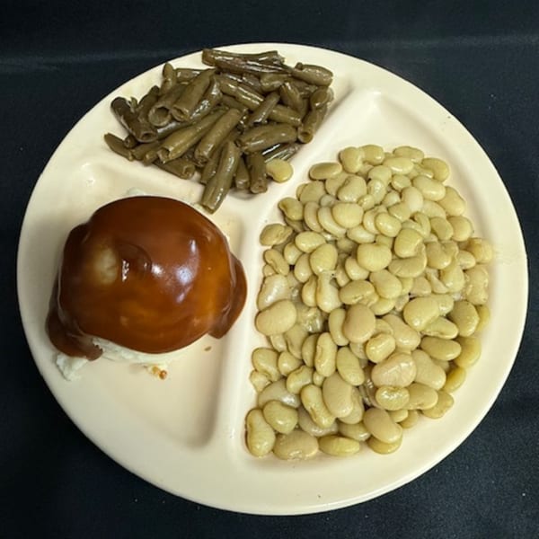 Diner plate with green beans, lima beans, and a biscuit with brown gravy.