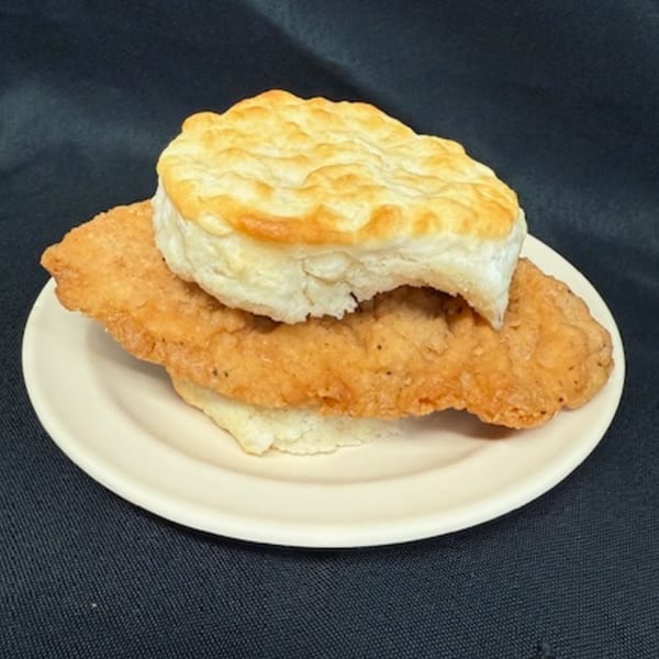 A golden-brown fried chicken fillet and a fluffy biscuit on a white plate from Lovick's Cafe.