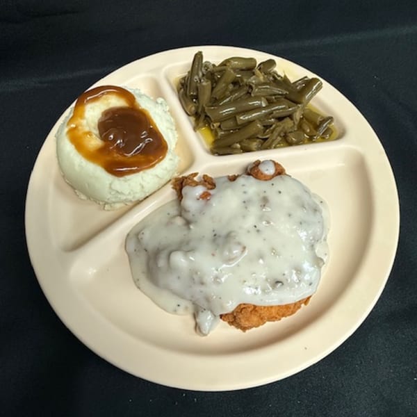 A diner plate with chicken fried steak, mashed potatoes with gravy, and green beans.