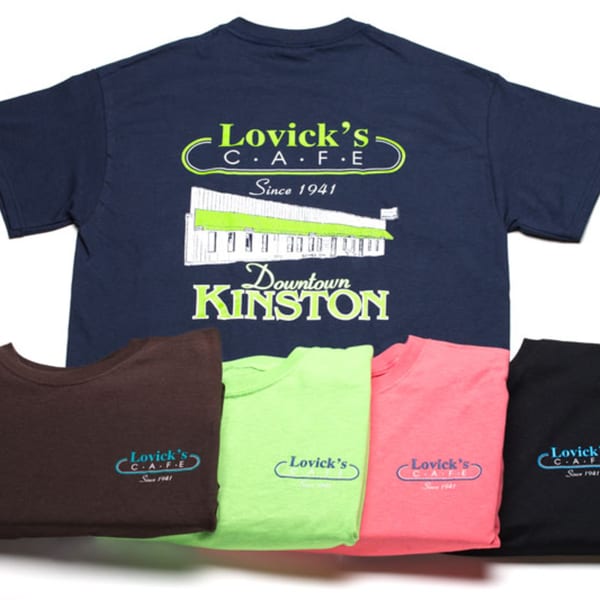 A navy blue Lovick's Cafe t-shirt with a diner illustration, surrounded by four other colored shirts.
