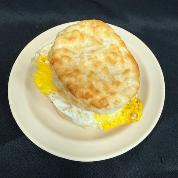 A golden-brown biscuit with a fried egg on a light plate, ready to eat at Lovick's Cafe.